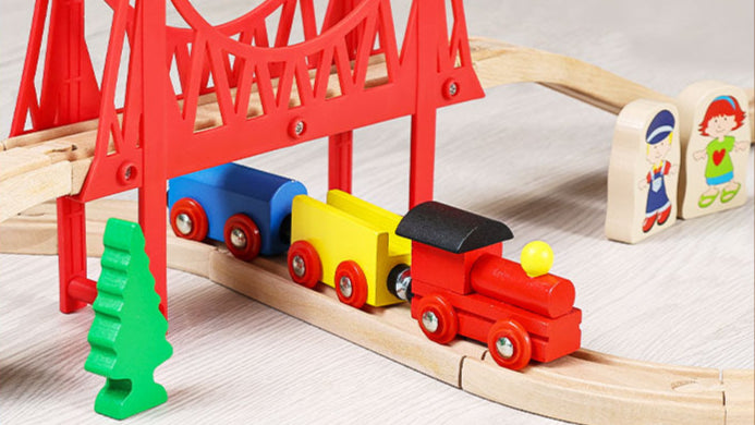 Colorful toy train set on a wooden track with a red bridge