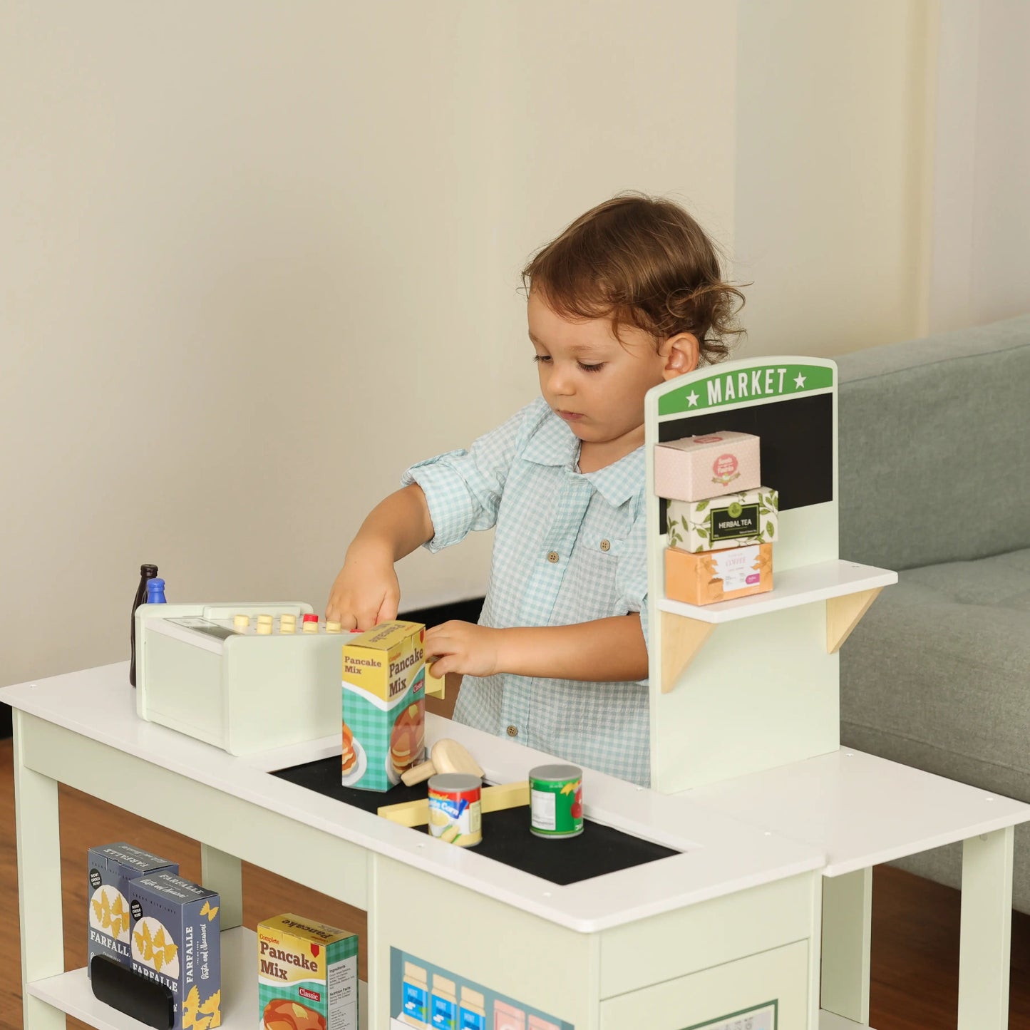 Child playing with a toy kitchen set in a living room.