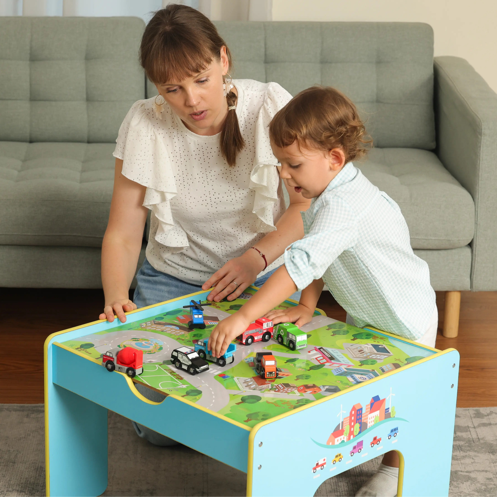 Woman and child playing with toy cars on a colorful table in a living room.