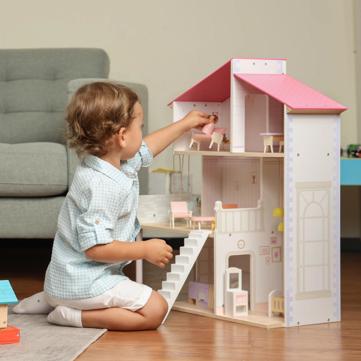 Child playing with a dollhouse in a living room
