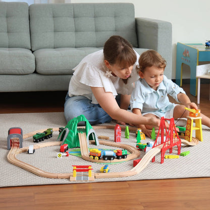 Two children playing with a toy train set on the floor in a living room.