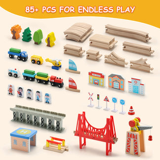 Collection of toy train tracks, cars, and buildings on a beige background with text '85+ PCS FOR ENDLESS PLAY'.