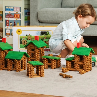 Child playing with lincoln logs wooden houses and blocks on a carpeted floor.