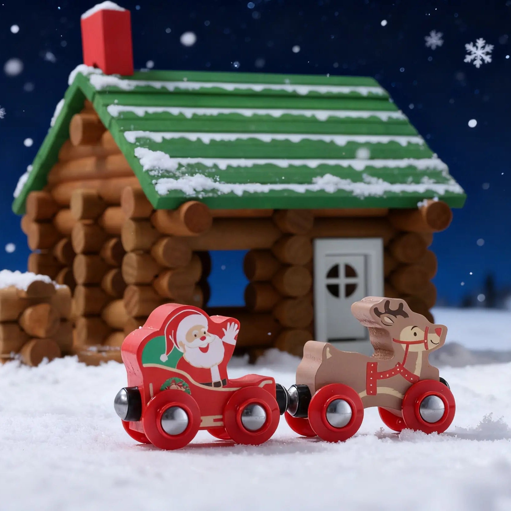 Toy train with Santa Claus passing a wooden cabin in a snowy landscape