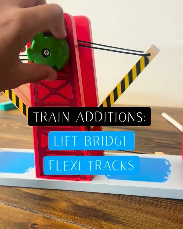 Hand interacting with a toy train set on a wooden surface, featuring text about train additions.