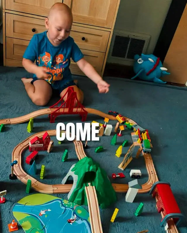 Child playing with a toy train set on a blue carpet