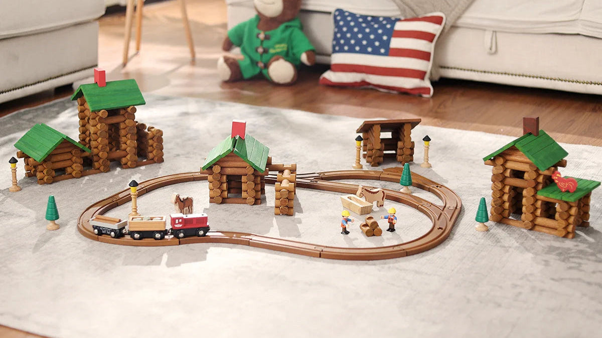Toy train set with wooden log cabins on a living room floor