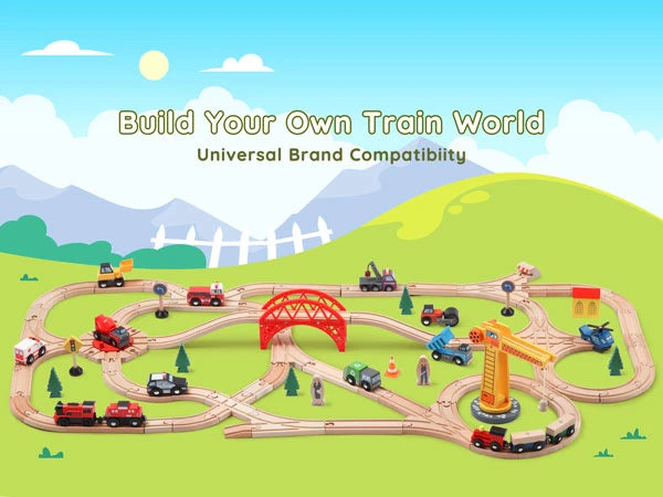 Toy train set with tracks and vehicles on a green landscape with mountains and a blue sky.