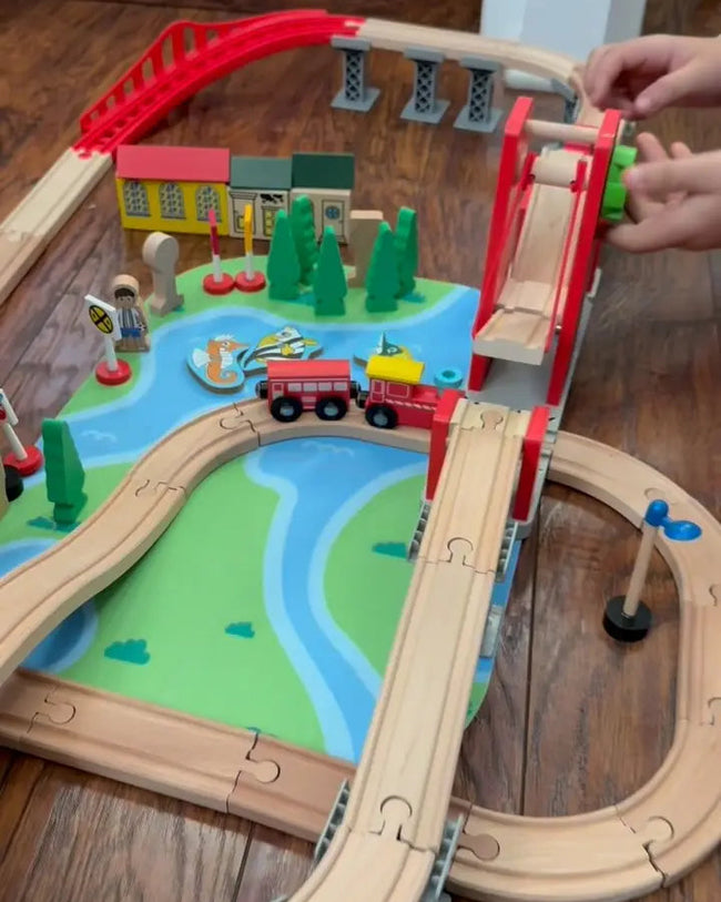 Wooden train set with tracks and accessories on a wooden floor