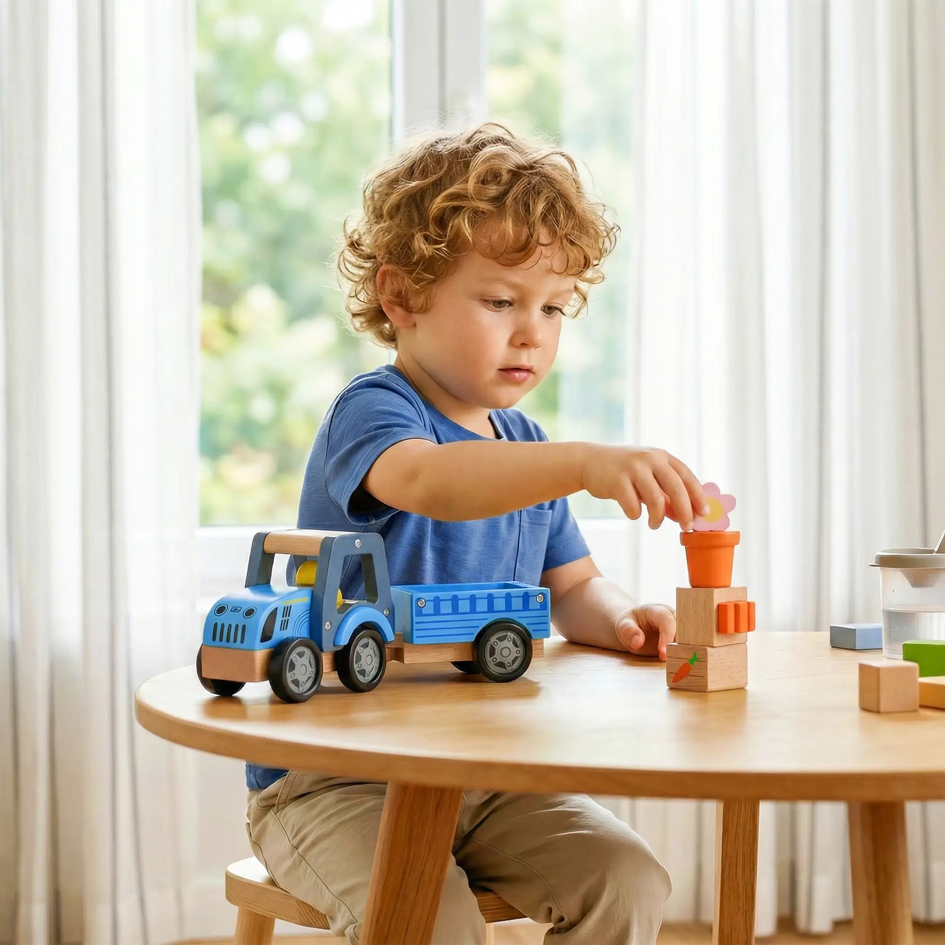 Child playing with a blue toy truck and wooden blocks